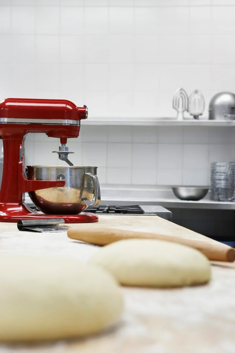 Dough on wooden board, beside dough mixer in kitchen
