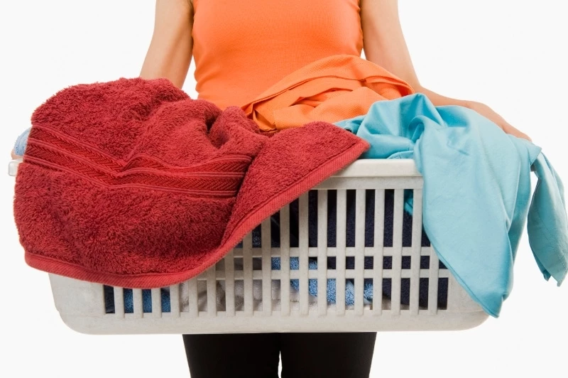 Mid section view of a woman holding laundry basket filled with clothing