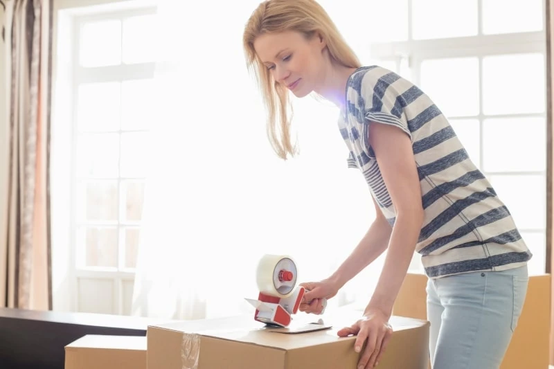 Woman packing moving box at home