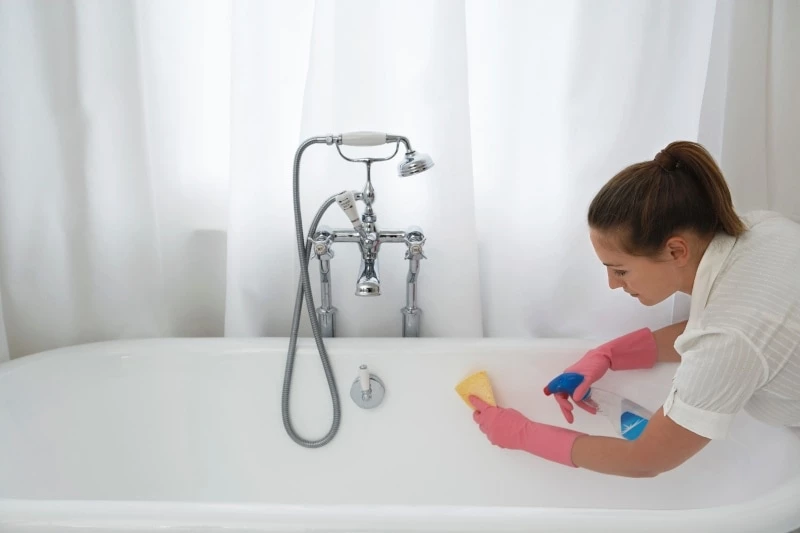 Woman cleaning a white tub