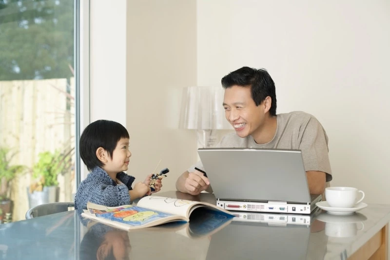 A father teaching a son at a kitchen table