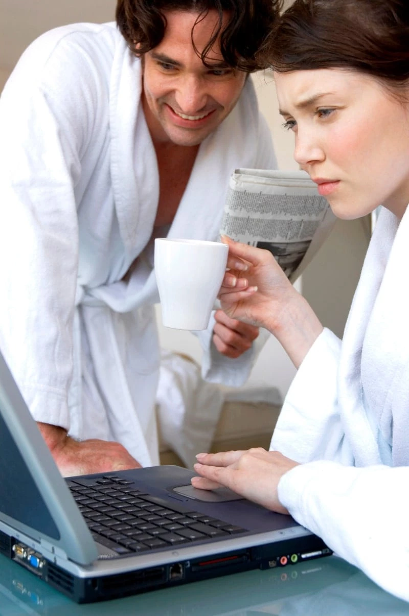 Husband and wife in white robes looking at a laptop screen