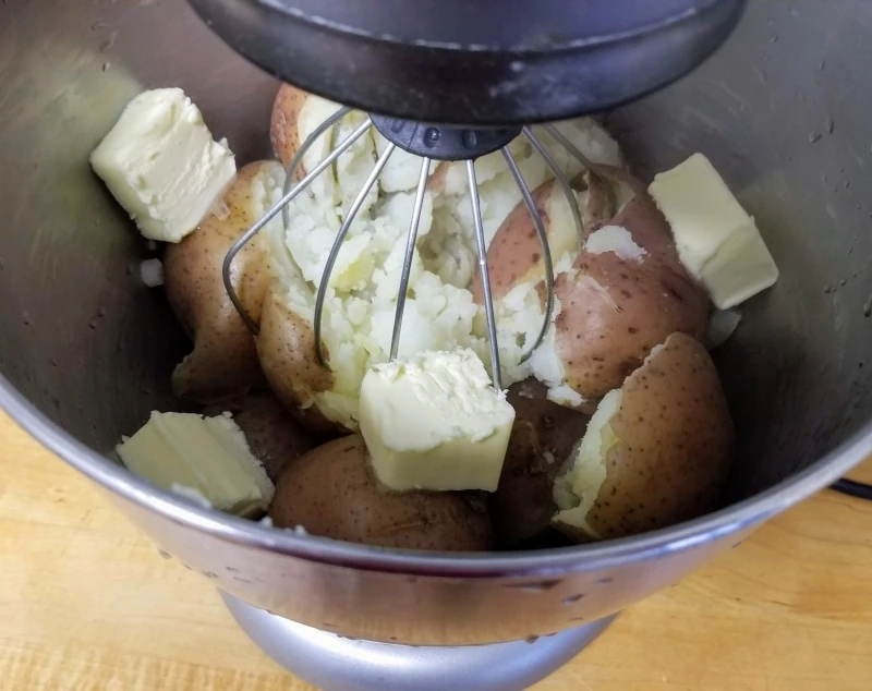 Potatoes with slices of butter in KitchenAid Mixer