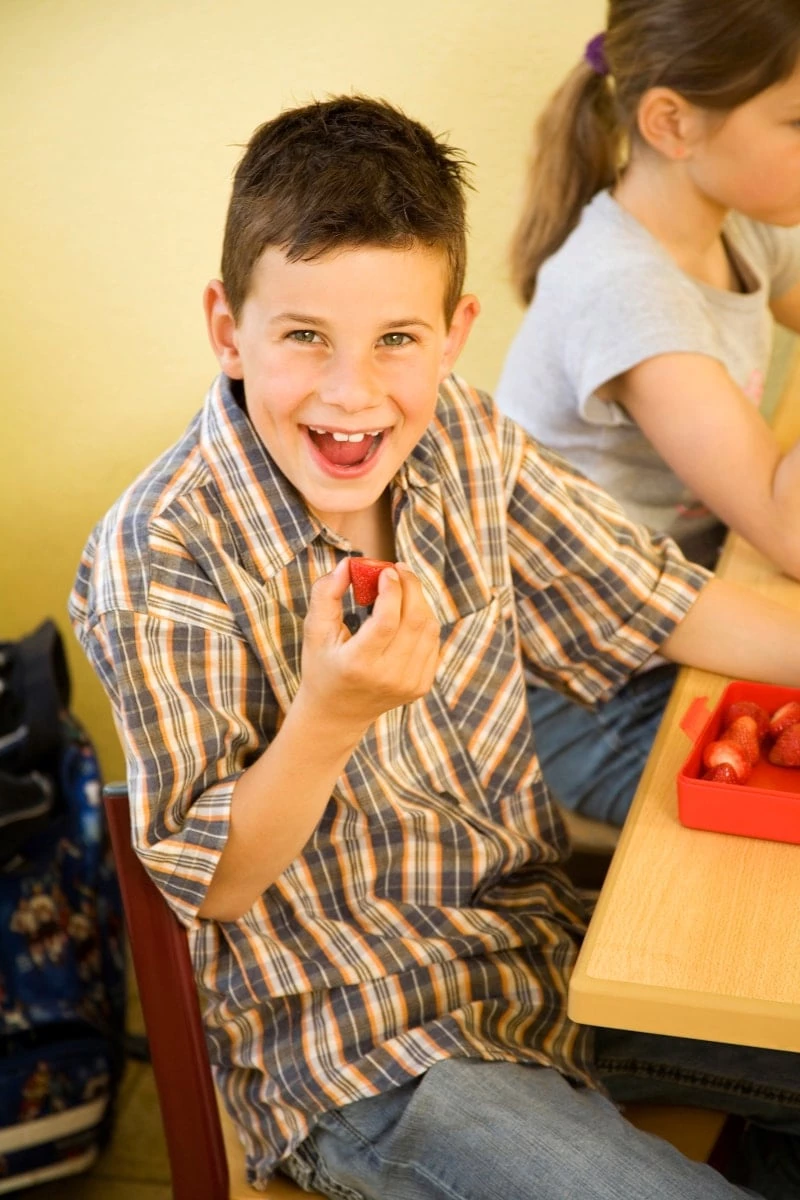 Boy smiling while eating a strawberry