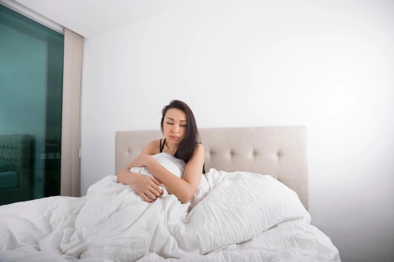 Depressed woman sitting in bed not wanting to get out of it