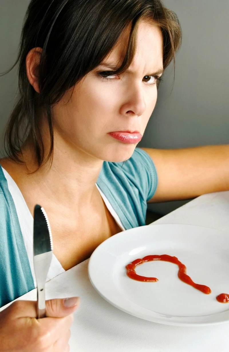 Woman wondering what's for dinner with a question mark drawn on a plate in ketchup