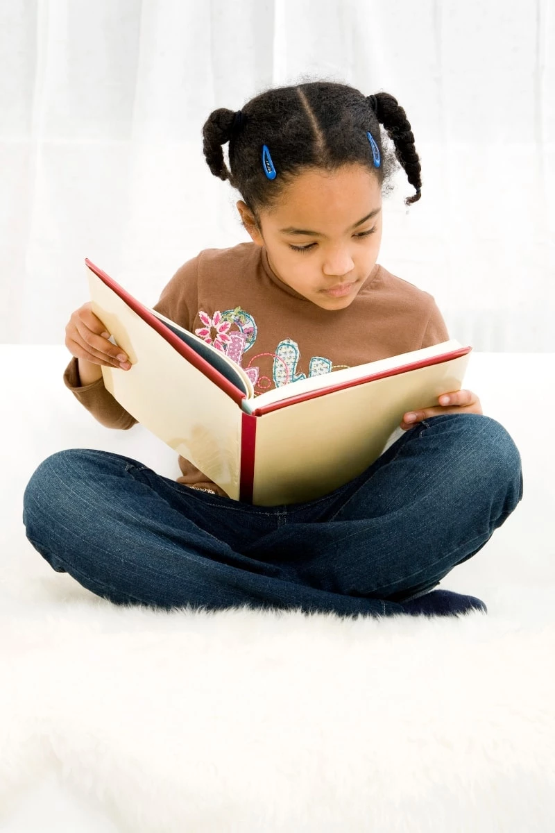 Young girl reading a book while sitting on the floor