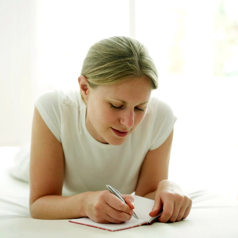 Woman journaling while laying in bed