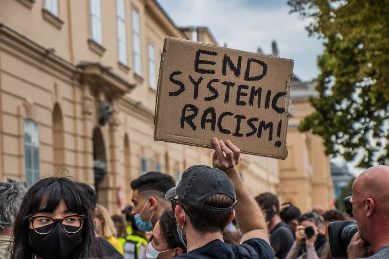 a person holding up a sign that says stop systemic racism