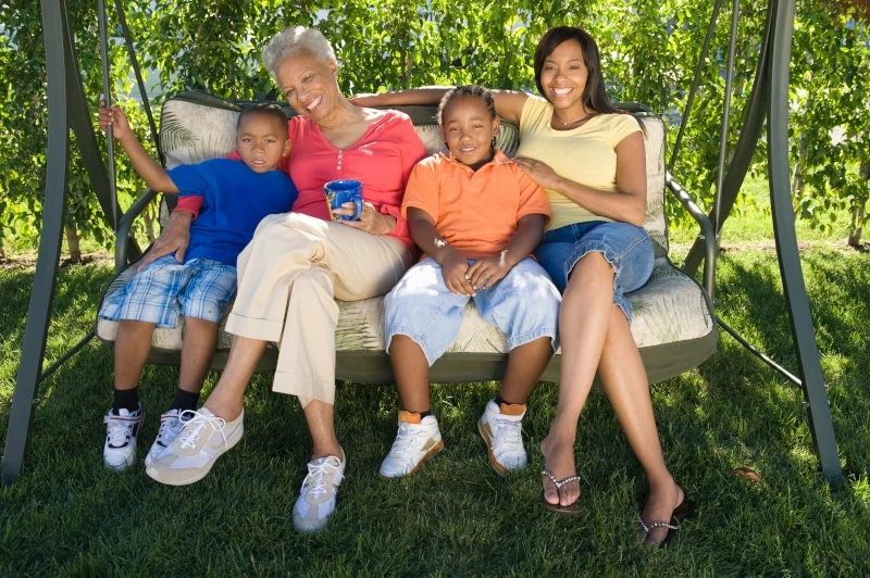 grandma, mom, and two young boys sitting on a swing together