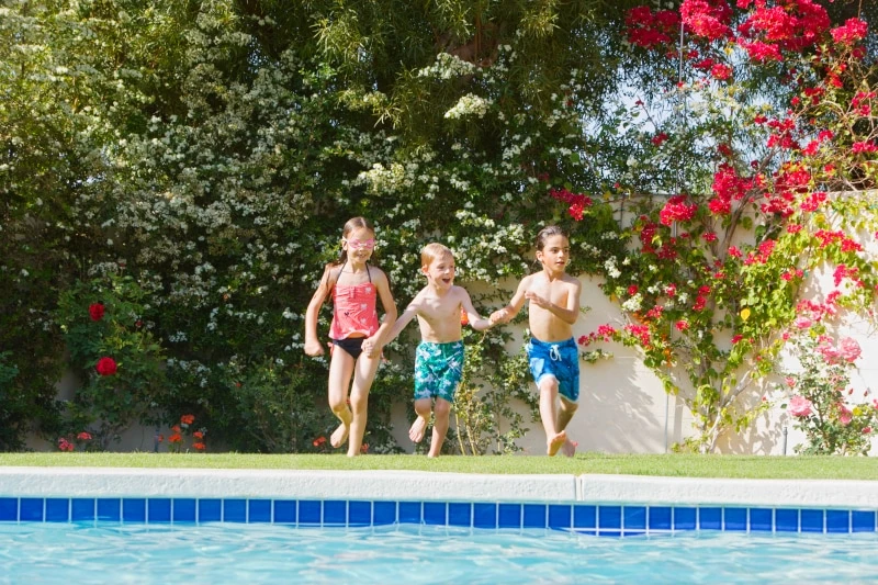 three children running towards a pool