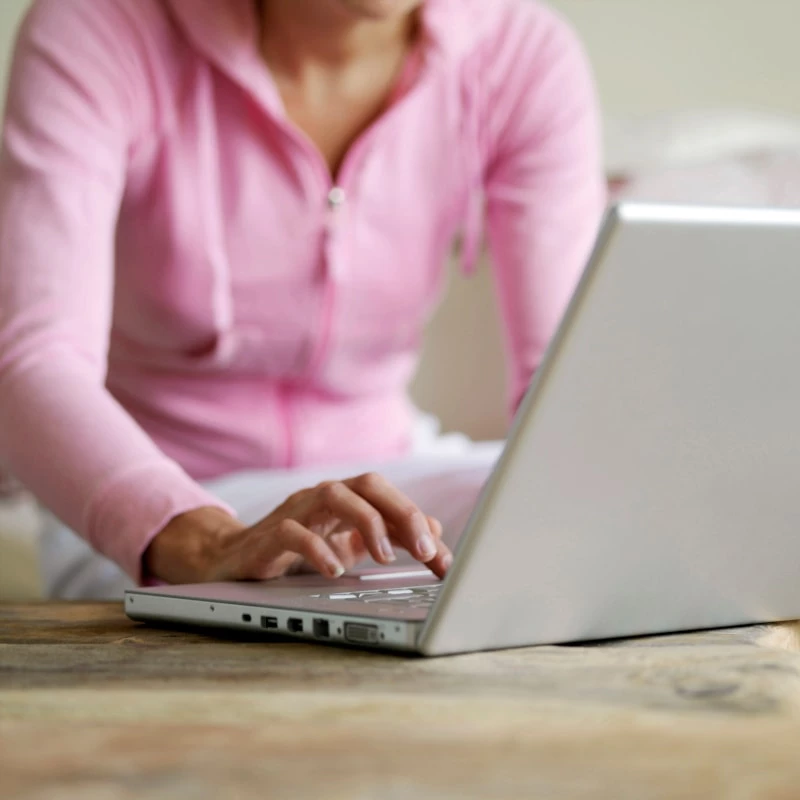 woman in pink sweater sitting in living room using a laptop