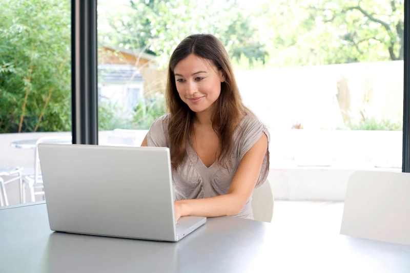 woman sitting at table using laptop