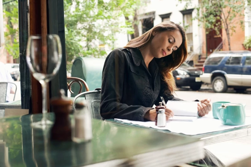 woman sitting in a cafe journaling