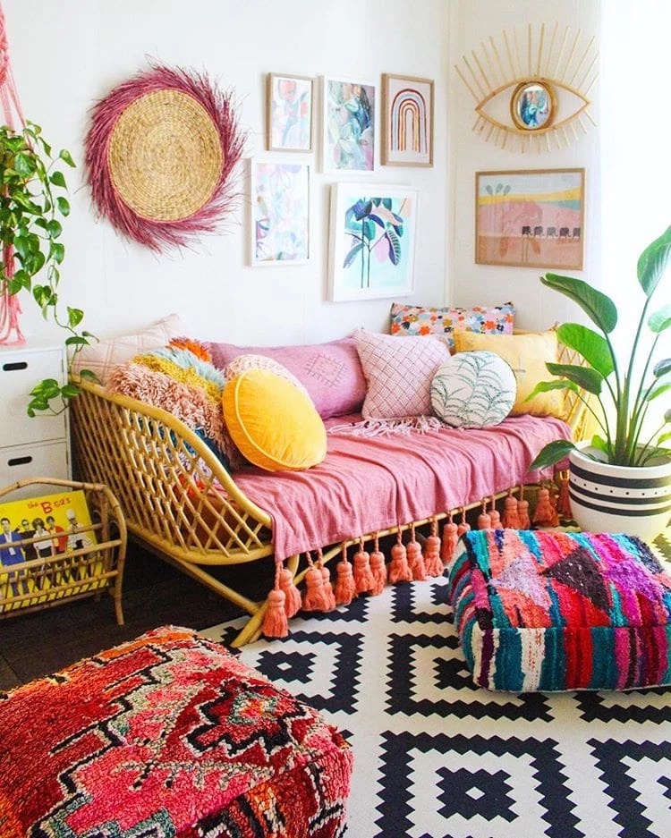 A boho chic living room that uses plenty of pink coloring. A gallery wall features more pink, green and navy blue modern and geometric prints.