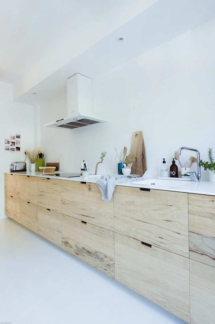 A scandinavian styled kitchen with natural wood tones and a white counter top.
