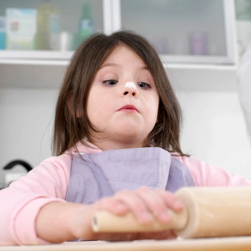 child with flour on her nose while baking
