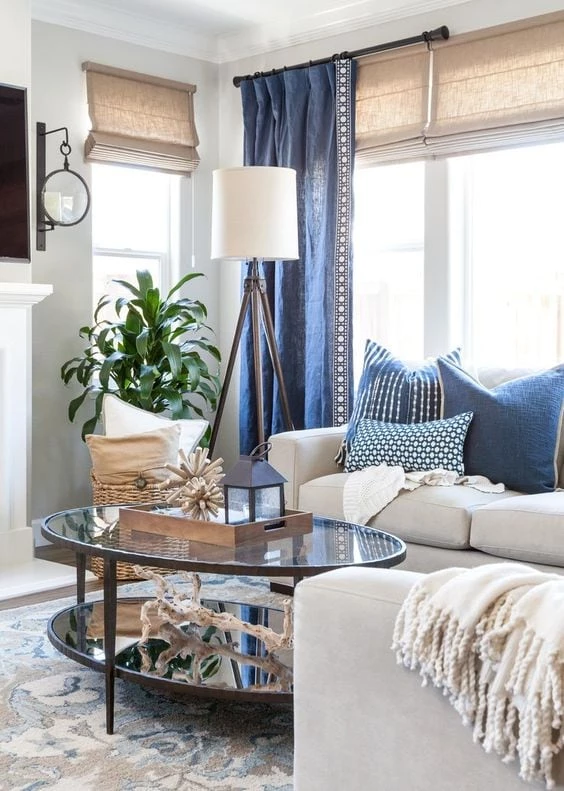 Living room with blue pillows and drapes and driftwood pieces on coffee table