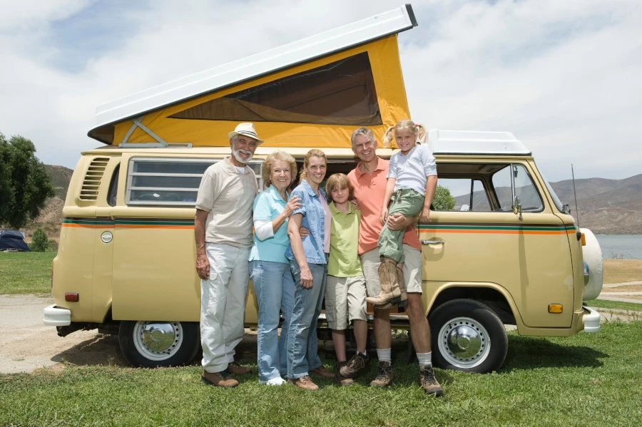 Grandparents with parents and grand children standing in front of a van style camper