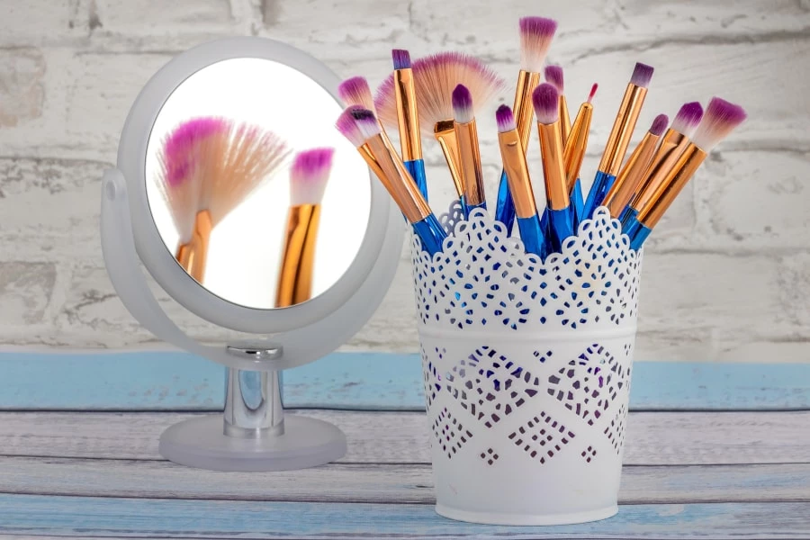 A cup with makeup brushes placed in front of a mirror