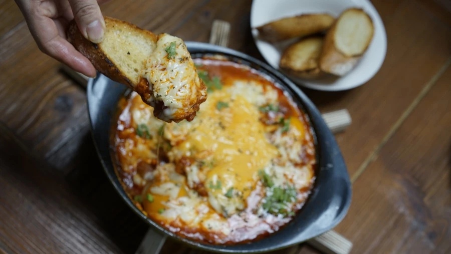 A person eat Shakshuka with bread