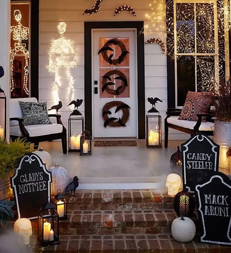 Front porch Halloween Decorations with tombstones, lit up skeletons, and candles