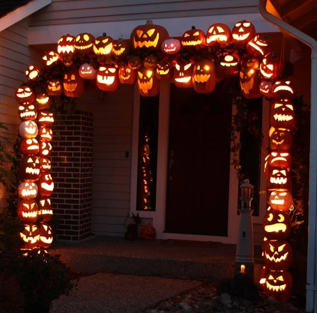An arch of jack o laterns over a front door.