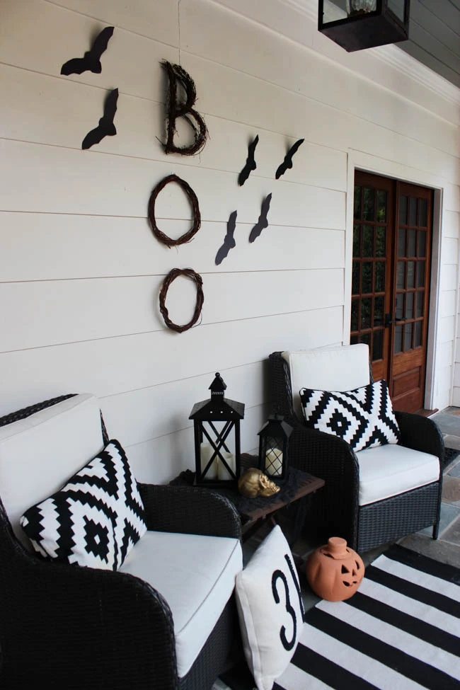 Boo spelled out in straw with paper bats and black and white accents on two chairs