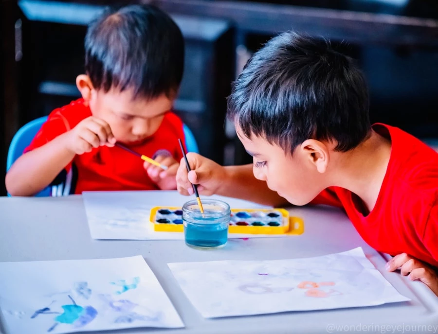Two boys in red shirts painting with water color paints