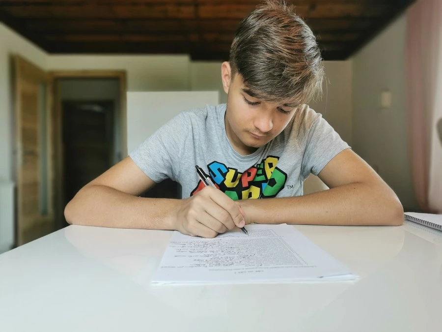 Boy writing on a piece of paper doing homeschooling