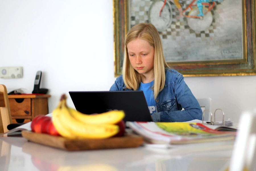 child sitting at a kitchen table with workbooks in front of her doing homeschooling