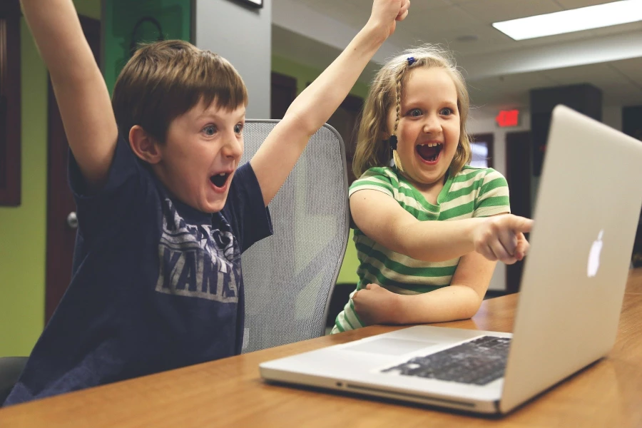 Two kids joyful while looking at a laptop screen