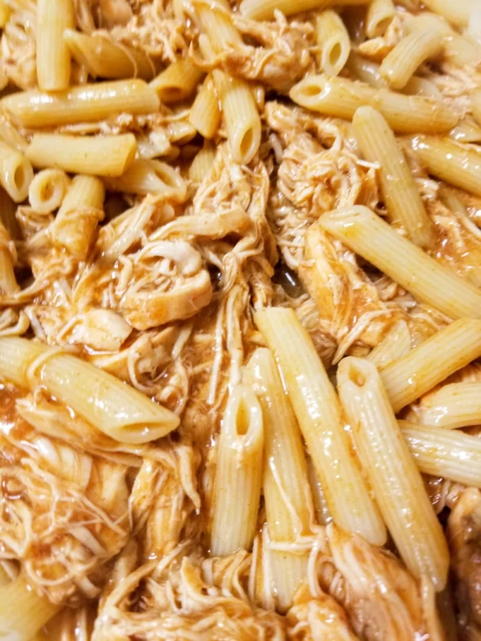 Chicken enchilada mixed with penne noodles in a glass pan