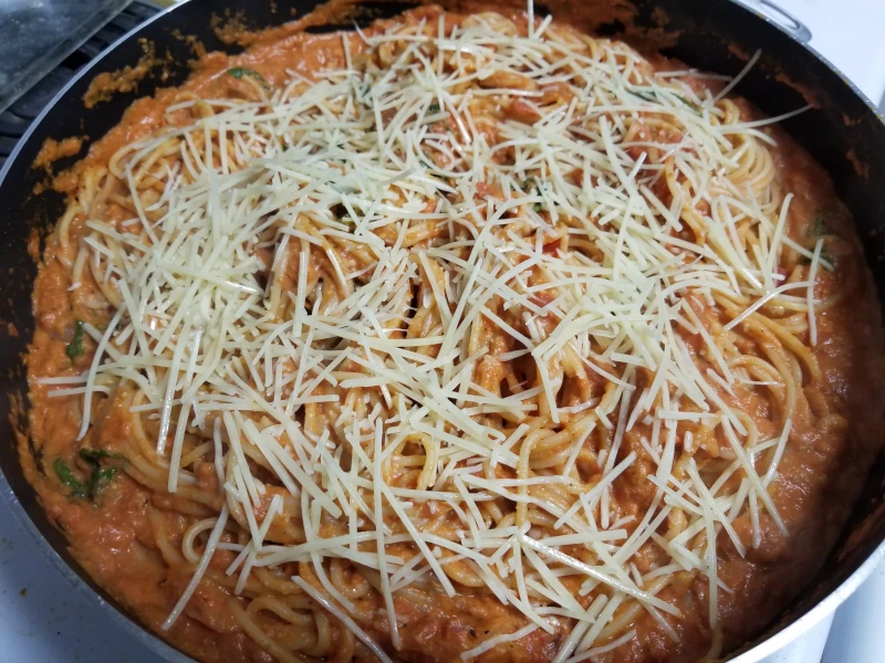 Creamy Tomato and Spinach Pasta in a pan garnished with parmesan cheese